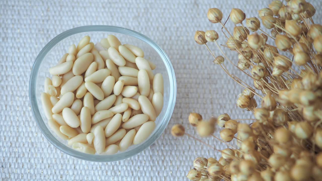 Pine nuts in a bowl with flax flowers