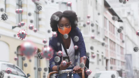 animation of covid 19 cells over african american woman in face mask using smartphone