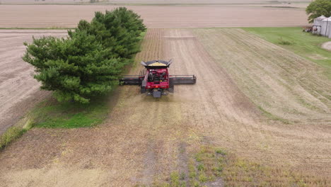 aerial of combine harvester collecting crop grains on a farm field