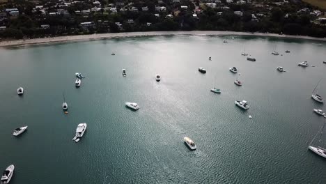 Aerial-view-of-the-town,-beach-and-bay-full-of-boats-at-Waiheke-island,-New-Zealand