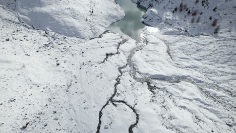 vista de drones del delta de un río glaciar congelado en los alpes desde un drone en invierno en un día soleado, italia