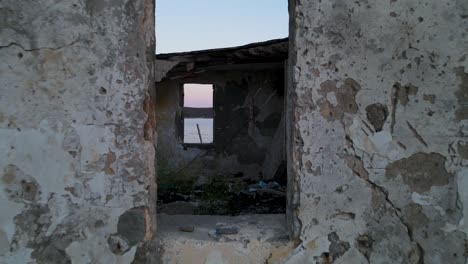 drone shot from inside an abandoned house facing the sea in porto palermo