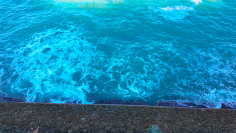 Vibrantes-Olas-Del-Océano-Turquesa-Rompiendo-Contra-Un-Malecón-En-Cádiz,-España