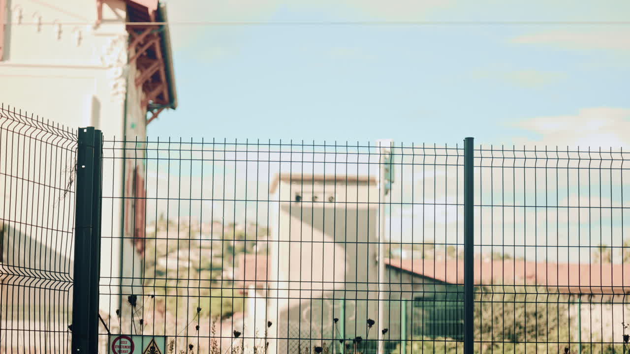 Blurred high speed train with colorful graphics rushes past behind a metal fence, conveying motion, travel and urban transportation infrastructure
