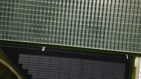 Industrial-greenhouse-and-solar-panel-farm,-aerial-top-down-view