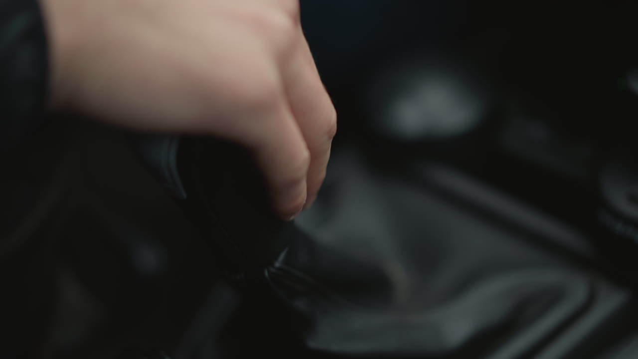 Close up of motorist hand shifting gear lever in smooth expert practiced motion, wrist and knuckles moving stick through gears, highlighting driver control and mechanical precision