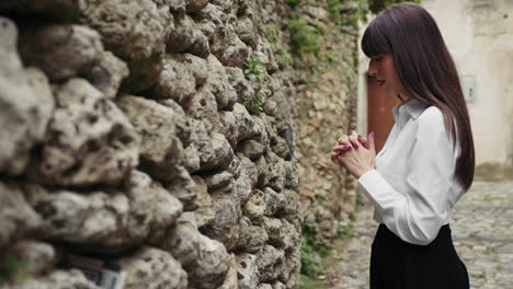 woman praying with passion in front of the old sacred wall