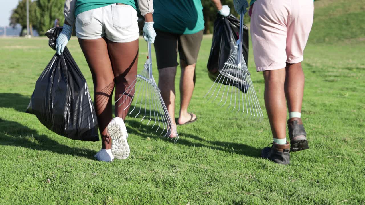 Cropped shot of volunteers with garbage bags and rakes