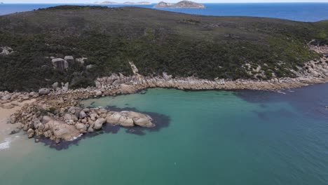 Panorámica-Aérea-De-Drones-Sobre-El-Hermoso-Agua-Azul-Oscuro-Y-La-Montaña-Verde-En-Un-Día-Soleado-En-El-Promontorio-De-Wilson