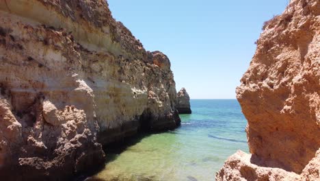 playa praia dos tres irmaos, algarve, portugal - tiro aéreo de drones volando a lo largo de las formaciones rocosas en la playa