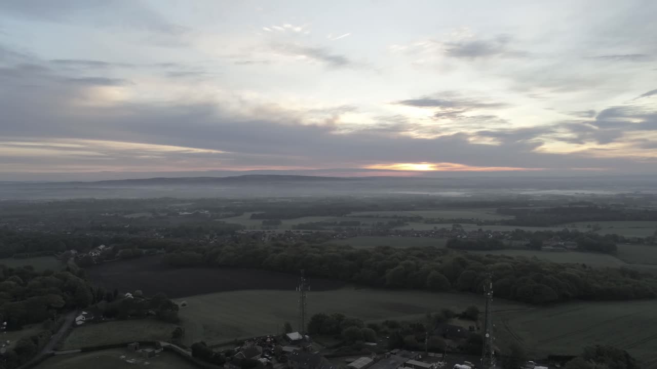 Early sunrise aerial telecom towers on agricultural rural farmland countryside slow lowering orbit left