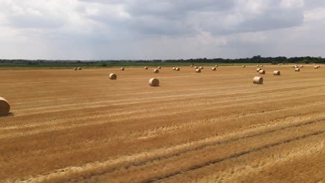 Aerial-orbit-shot-above-harvested-hay-field-with-round-straw-bales