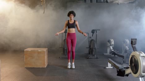 Mujer-Afroamericana-En-Forma-Feliz-Saltando-Con-Cuerda-De-Saltar,-Entrenamiento-Cruzado-En-El-Gimnasio,-En-Cámara-Lenta