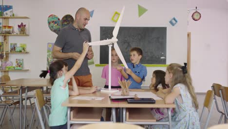 elementary school stem robotics classroom diverse group of children building and programming windmill ecology robot concept. together talking and working as a team. creative robotics engineering