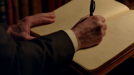 close-up of hands writing in a book with a pen