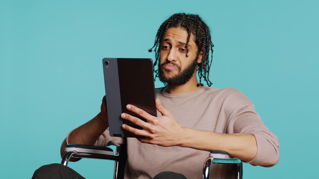 Person with paraplegia using tablet for social media, studio background