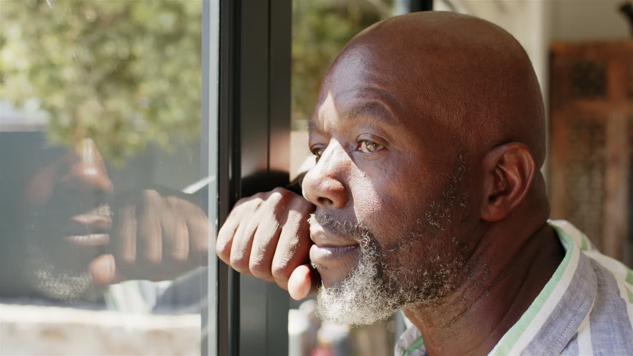 Looking out window, pensive African American man reflecting and contemplating life, copy space