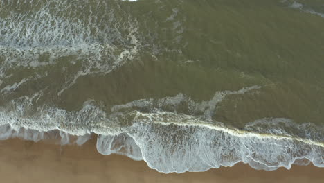 powerful, agitated sea with high waves constantly crashing on an empty, secluded beach