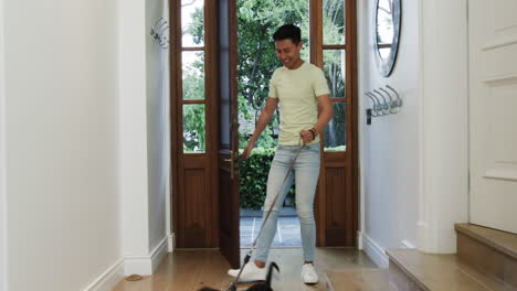 asian man entering home with playful dog on leash, smiling happily