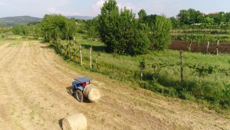 campo agricolo in azienda con trattori che producono paglia durante la raccolta