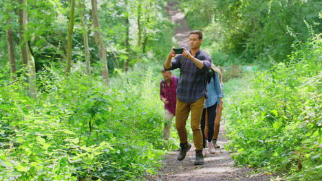 group of friends posing for selfie in countryside taking picture on phone as they hike along path