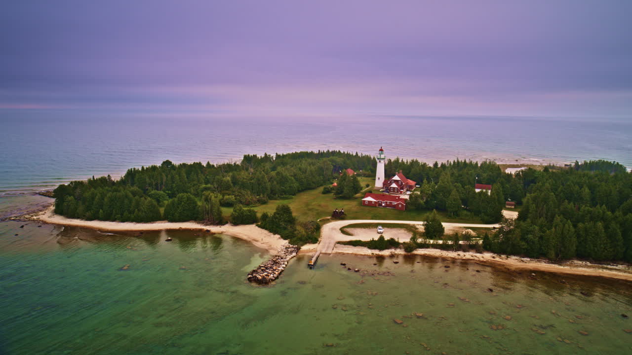 Drone shot panning around lighthouse that sits on the edge of Lake Michigan