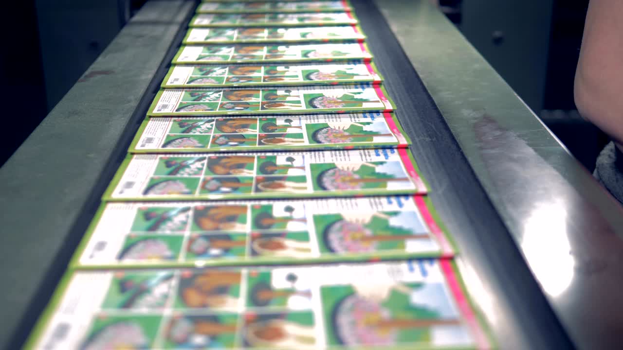 Close up of magazines moving along the conveyor belt, getting collected and put away by an employee