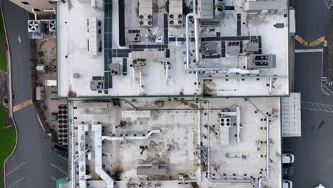 aerial top view of industrial rooftop filled with hvac systems and ventilation pipes. complex layout of machinery and pathways. urban infrastructure from above. clean lines and geometric patterns.