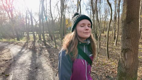 fit outdoor woman walks in forest on sunny fall day, slomo follow shot