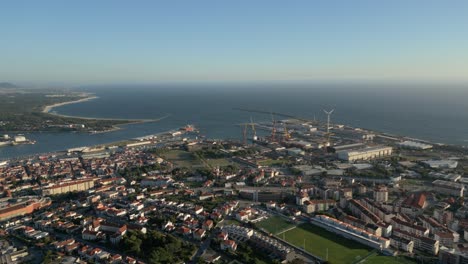 coastal cityscape viana do casteçp overlooking river, ocean, and industrial port with wind turbines. portugal