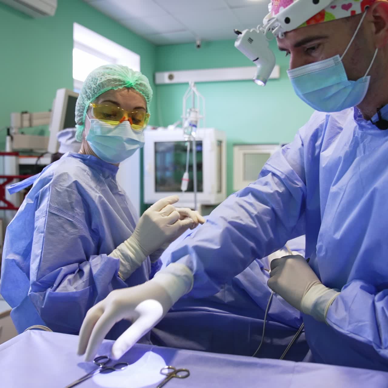 Male Caucasian surgeon carries out the thyroid surgery. Female doctor assisting and arranging the tools
