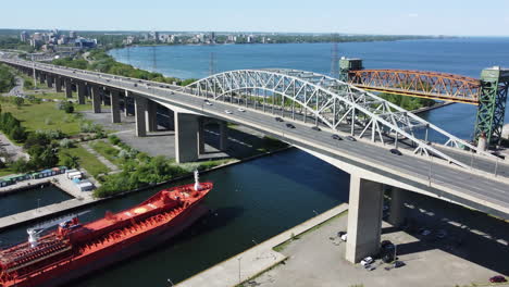 Large-boat-passing-over-busy-highway-towards-elevated-bridge---Ontario,-Burlington