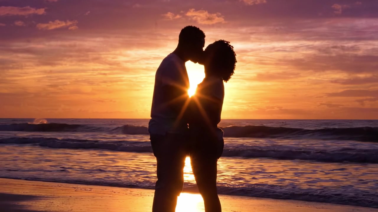 Un Tramonto Romantico: Una Coppia che si Abbraccia sulla Spiaggia mentre il Sole Tramonta, Irradiando Colori Caldi sull'Orizzonte, Catturando un Momento di Amore e Connessione
