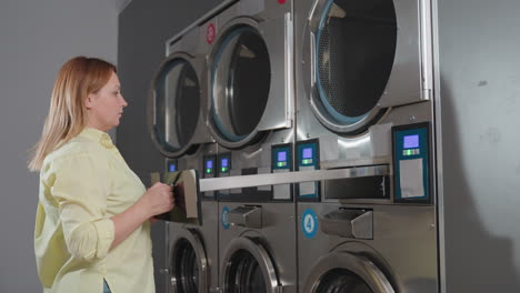 laundry owner closes industrial washer filter drawer after inserting cleaned inner filter, pushes unit back into compartment, locks with key, ensures routine maintenance in laundromat environment