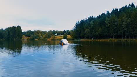 a-drone-flies-low-over-the-lake-against-a-floating-platform-aerial-view