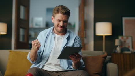 Ganador-Lleno-De-Alegría-Haciendo-Un-Gesto-De-Sí-En-El-Interior-De-Casa.-Hombre-Emocionado-Regocijándose-Tablet