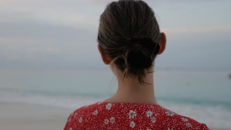 slow motion shot of brown haired caucasian woman in red dress looking out over the ocean on beach at asu island, north sumatra, indonesia