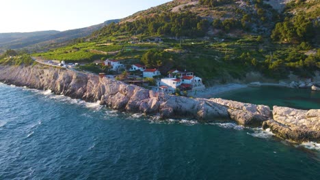 vista de un pueblo costero con muchas casas con techos rojos, rodeado por el mar y las montañas con yates en marina bay y bell towe