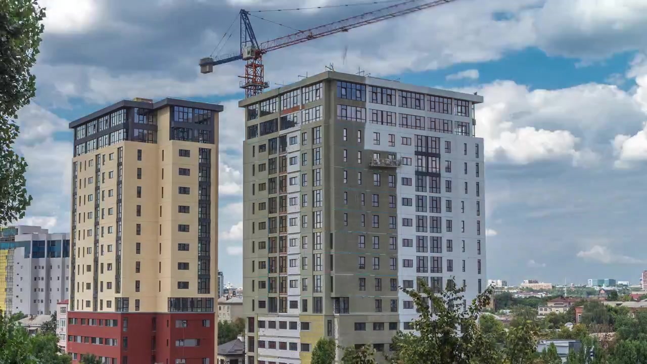 Gru e cantiere edile contro il cielo blu timelapse aereo. Operai che tinteggiano le pareti di una nuova casa residenziale