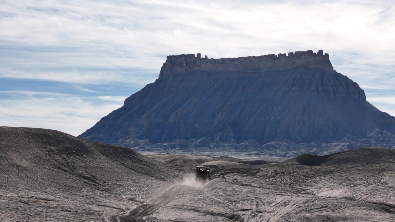 Ripresa con drone di un veicolo ATV che solleva polvere sulla strada per Factory Butte, Utah USA