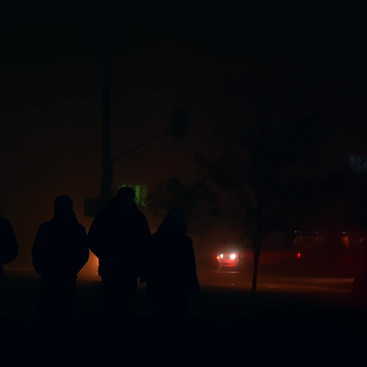 Pedestrians walking by the dark sidewalks of metropolis. Ukrainian energy crisis from russian missiles destroying power stations