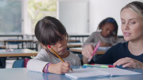 Maestra-De-Escuela-Caminando-Hacia-Una-Alumna-En-Clase