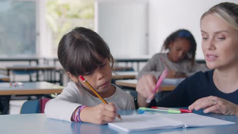 maestra de escuela caminando hacia una alumna en clase