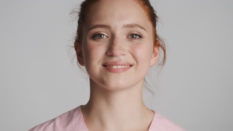 redheaded doctor in front of camera on gray background.