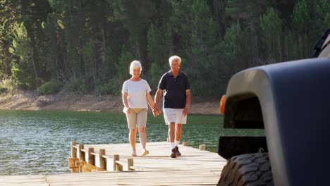 senior couple walking back on jetty after admiring lake view