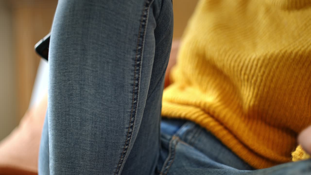 Unrecognizable Woman Sitting On A Couch With A Cellphone. Close-up Shot