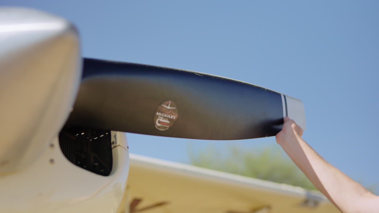 Pilot's Hand Rotating Airplane Propeller During Pre-Flight Check