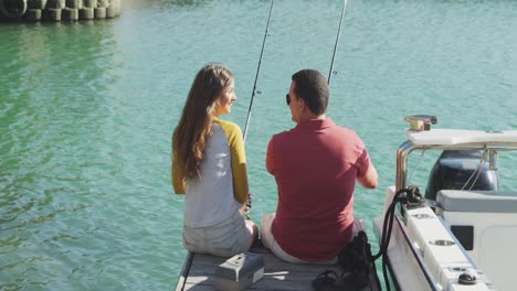 rear view of a caucasian man and his teenage daughter fishing harbor side