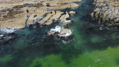 waves crashing on the rocky coast slide down drone footage