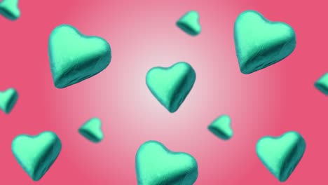 flying a heart shape wrapped chocolate candy flying and wiggle of different diameters on trending pink gradient background. concept of day of st. valentine's, weddings, birthday and other holiday